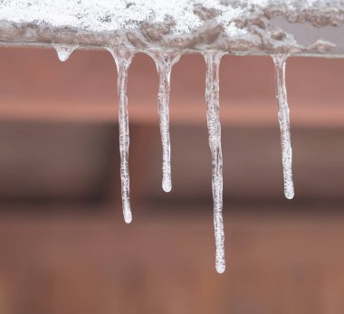 seçici odak teneke çatıdan aşağı asılı buz sarkıtları kapatın