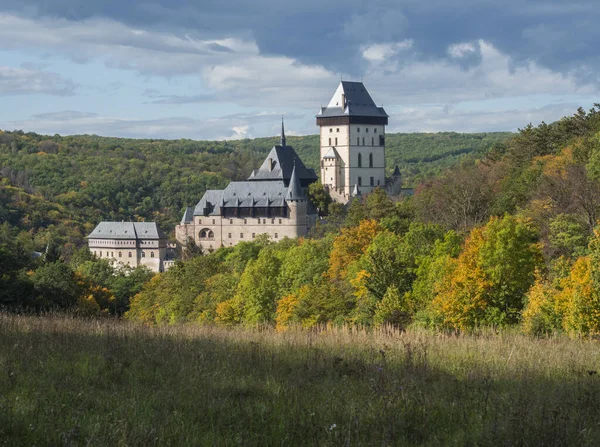 Karlstejn gotische Staatsburg in der Nähe von Prag, die berühmteste Burg in der Tschechischen Republik mit Graswiesen und Herbst farbigen Bäumen und Wäldern. blauer Himmel Wolken Hintergrund. in der Nähe von Prag. — Stockfoto