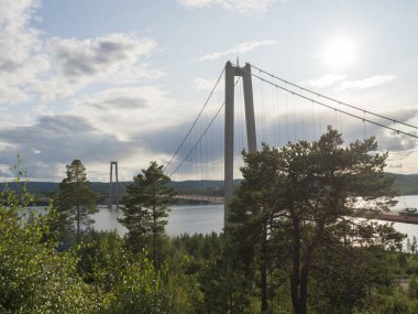 İsveç, Vaesternorrland yakınlarındaki Angermanalven nehrinin kuzey kıyısından görülen Yüksek Sahil Köprüsü 'nün yaz manzarası.