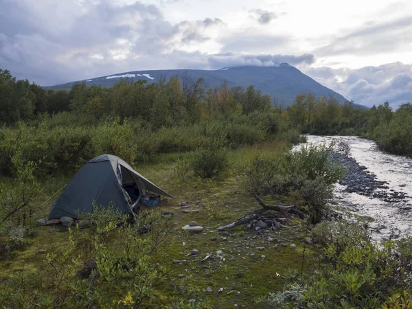 Piccola tenda verde in bellissimo paesaggio naturale della Lapponia selvaggia con fiume blu, betulle e montagne. Estate della Svezia settentrionale al sentiero escursionistico Kungsleden. Cielo blu nuvole drammatiche — Foto Stock