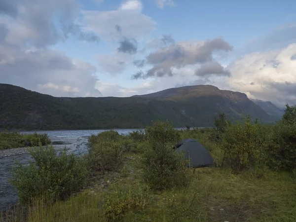 Kleine groene tent in Prachtige wilde Lapland natuur landschap met blauwe rivier, Teusajaure meer, berken bomen en bergen. Noord-Zweden zomer op Kungsleden wandelpad. Blauwe lucht dramatische wolken — Stockfoto