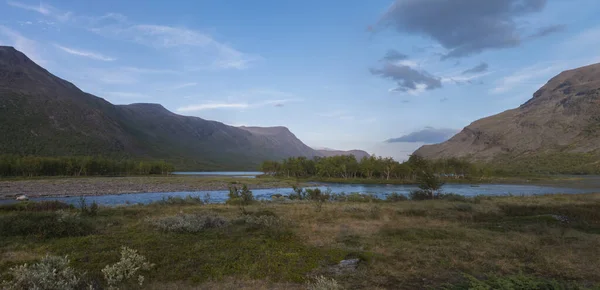 Geniş panoramatik Laponya doğa manzarası içinde vahşi Tjaktjajakka nehri ve küçük huş ağacı ormanı adası ve dağları ile Kaitumjaure gölü bulunuyor. Kuzey İsveç 'te yaz mevsimi. — Stok fotoğraf