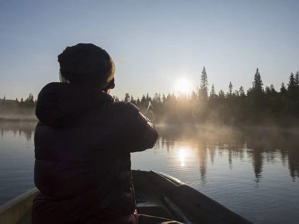 Pescador en bote de remos en el lago Sjabatjakjaure en Hermosa niebla soleada mañana neblina en Suecia Laponia naturaleza. Montañas, abedules, bosques de abetos. Blu cielo y contraluz —  Fotos de Stock