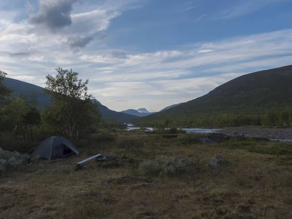 Mały zielony namiot w pięknej dzikiej Laponii krajobraz przyrody z niebieską rzeką, jezioro Kaitumjaure, brzozy i góry. Północna Szwecja lato na szlaku turystycznym Kungsleden. Błękitne niebo dramatyczne chmury — Zdjęcie stockowe