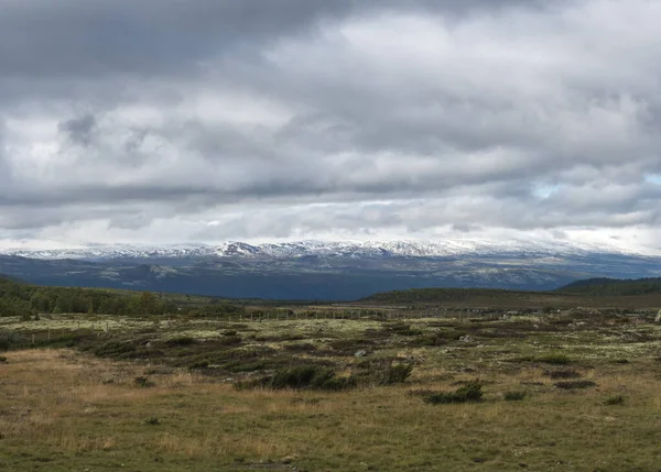 Vue d'automne sur les collines et les montagnes enneigées avec des nuages spectaculaires au parc naturel Dovre Nasjonaalpark depuis la route principale E6, Norvège — Photo