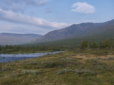 Mavi Tjaktjajakka nehri, Kaitumjaure, huş ağacı ormanı ve Sanjartjakka dağı ile güzel, vahşi Laponya tabiatı. Kuzey İsveç yazı Kungsleden yürüyüş parkurunda. Mavi gökyüzü arkaplanı