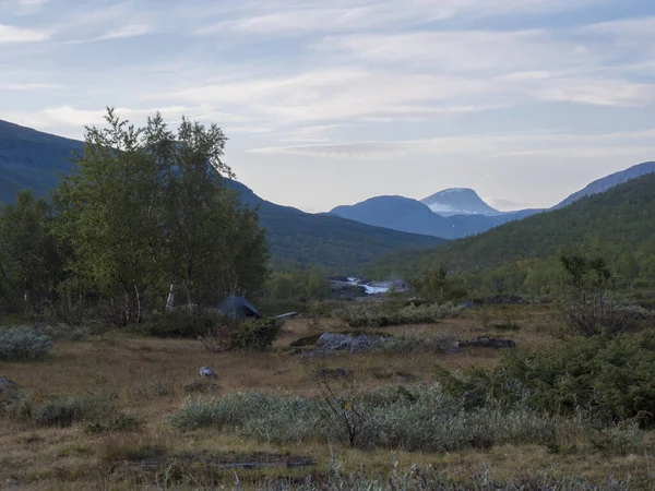 Beau paysage avec petite tente verte, cascade sur la rivière sauvage Tjaktjajakka, forêt de bouleaux et montagnes. Nature de Laponie en été au sentier de randonnée Kungsleden. Fond bleu ciel — Photo