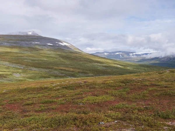 Landschap van Lapland natuur op Kungsleden wandelpad met kleurrijke bergen, rotsen, herfst gekleurde struiken, berken en heide in dramatisch licht en wolken — Stockfoto