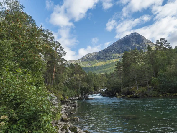 在绿松石山河上，斯诺特维尔瓦瀑布与森林和山脉相连，发源于挪威融化的冰川。 蓝天白云。 暑期旅游风景. — 图库照片