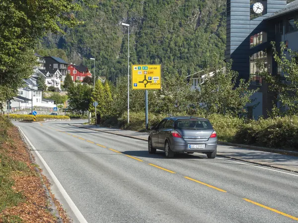 Sogndal, Norvège, 8 septembre 2019 : Voiture sur la route touristique nationale 55 avec panneau de signalisation et maisons de la ville de Sogndal, Norvège. Journée ensoleillée . — Photo