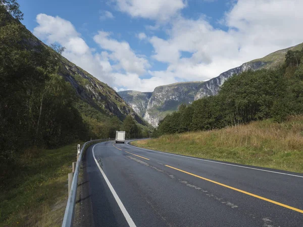 Vit husbil vid slingrande väg E136 med bergsmassiv Trolltindene, Trollveggen Trollveggen i Romsdal, Norge. Blå himmel, vita moln. Sommar resa resa landskap. — Stockfoto