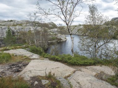 Preikestolen devasa uçurumuna giden küçük su birikintisi ya da göl manzaralı ünlü Norveç manzaralı Moody, sonbahar günü. Doğa ve seyahat geçmişi, tatil ve yürüyüş tatili kavramı.