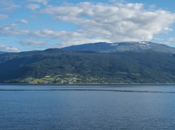 Vue sur l'eau bleue de Sogndalsfjorden Fjord Sogndal avec petit village sur la côte. Norvège, nature et antécédents de voyage. Début automne ciel bleu fond . — Photo