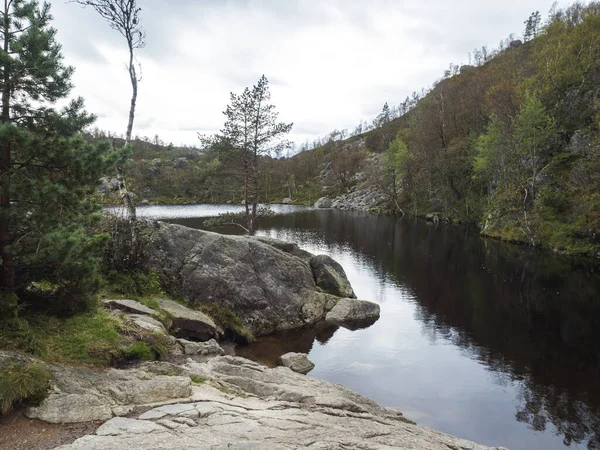 Kilátás a kis tavon vagy tavon túrázni Preikestolen hatalmas szikla híres norvég kilátást Moody ég, őszi napon. Természet és utazási háttér, nyaralás és túrázás nyaralás koncepció. — Stock Fotó