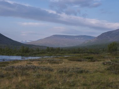 Mavi Tjaktjajakka nehri, Kaitumjaure, huş ağacı ormanı ve Sanjartjakka dağı ile güzel, vahşi Laponya tabiatı. Kuzey İsveç yazı Kungsleden yürüyüş parkurunda. Mavi gökyüzü arkaplanı