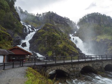 İkiz şelale Latefoss ya da Latefossen ve Norveç 'in Odda Hordaland ilçesi, 13. karayolu boyunca altı kemerli köprü. Sonbaharın başı, karamsar gökyüzü