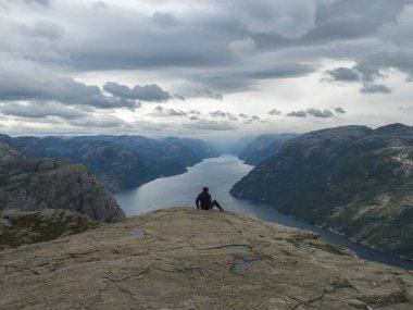 Norveç 'in ünlü uçurumundan fiyort Lysefjord' un manzarasına hayran olan yürüyüşçü kadın. Huysuz bir sonbahar günü. Doğa ve seyahat geçmişi, tatil ve yürüyüş tatili kavramı.