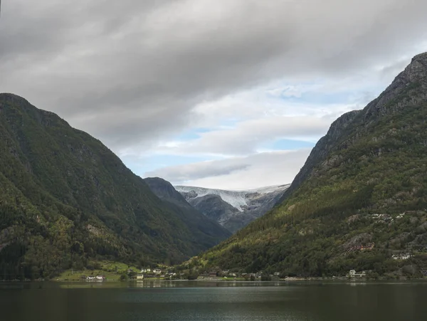 Blick über das blaue Wasser des Hardanger-Fjords in Kinsarvik auf dem Folgefonna-Gletscher mit kleinem Dorf an der Küste. Norwegen Natur und Reise Hintergrund. Frühherbsttag. — Stockfoto