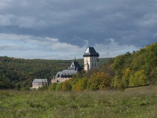 Karlstejn castelo de estado gótico perto de Praga, o castelo mais famoso da República Checa com grama prado e outono árvores coloridas e floresta. Céu azul nuvens fundo. Localizado perto de Praga . — Fotografia de Stock