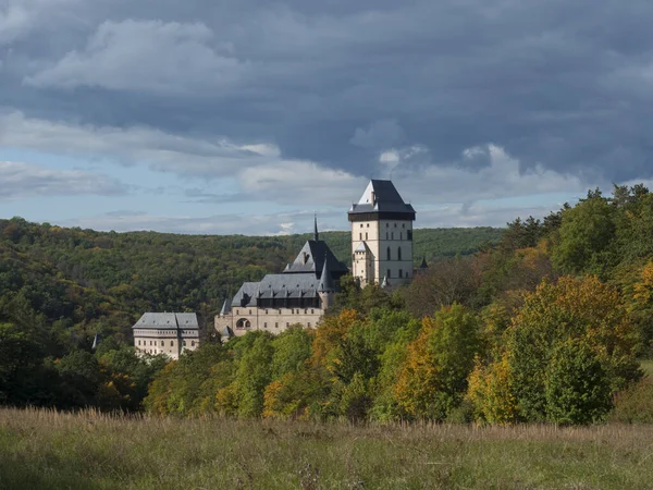 Karlstejn castelo de estado gótico perto de Praga, o castelo mais famoso da República Checa com grama prado e outono árvores coloridas e floresta. Céu azul nuvens fundo. Localizado perto de Praga . — Fotografia de Stock