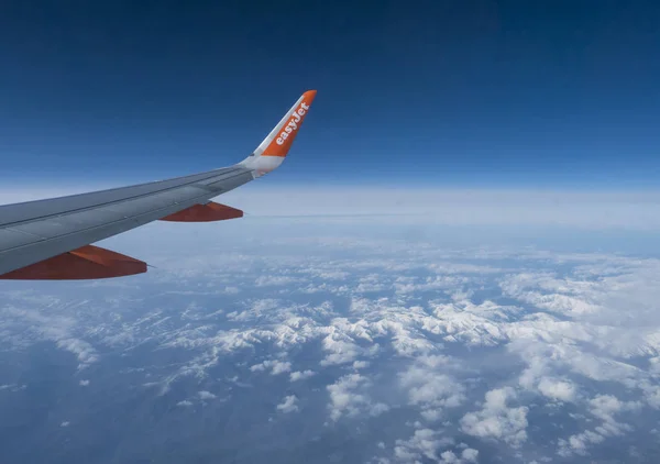 Pireneler, İspanya, 17 Aralık 2019: Easyjet havayollarının kanadındaki uçak penceresinden hava manzarası ve karla kaplı Fransız ve İspanyol pireneleri. Mavi gökyüzü beyaz bulutlar