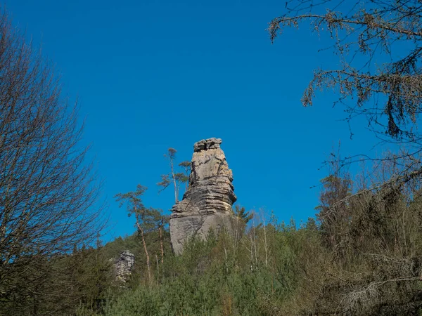 Piedra arenisca pilar en el paisaje de primavera r Lusacia Montañas con fresco bosque de árboles de abeto y caducifolios. Fondo cielo azul, espacio de copia — Foto de Stock