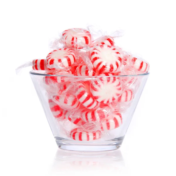 Peppermint candy in glass bowl isolated on white. Red striped mint