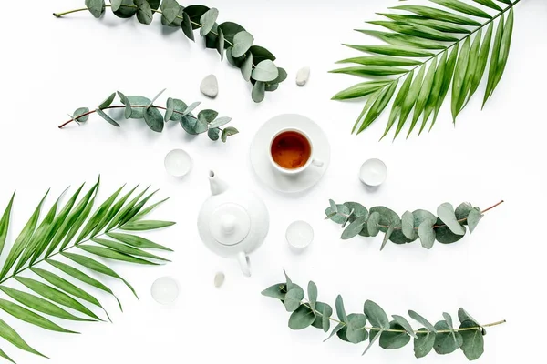 Czajniczek, kubek herbaty i gałęzie liści palmowych, płaskie układanie, widok z góry — Zdjęcie stockowe