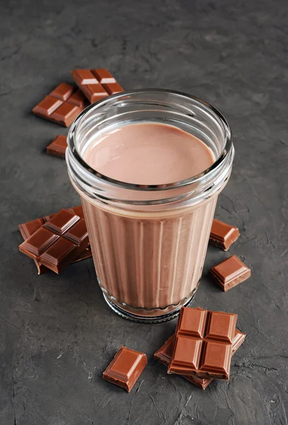 Chocolate milk and pieces of chocolate bar and cocoa beans — Stock Photo, Image
