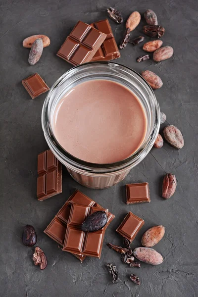 Chocolate milk and pieces of chocolate bar and cocoa beans — Stock Photo, Image