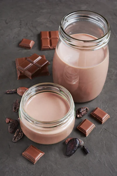 Chocolate milk with pieces of chocolate bar and cacao beans — Stock Photo, Image