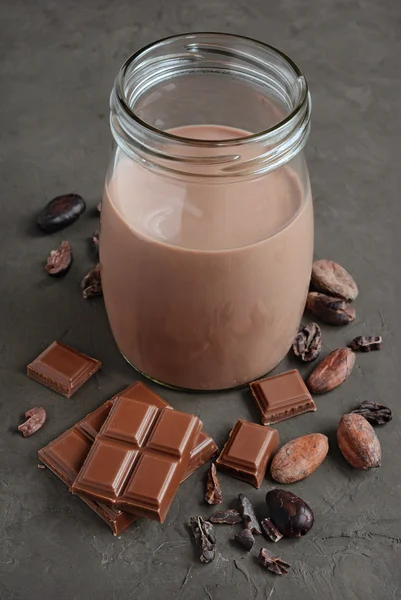 Leche de chocolate con trozos de barra de chocolate y granos de cacao — Foto de Stock