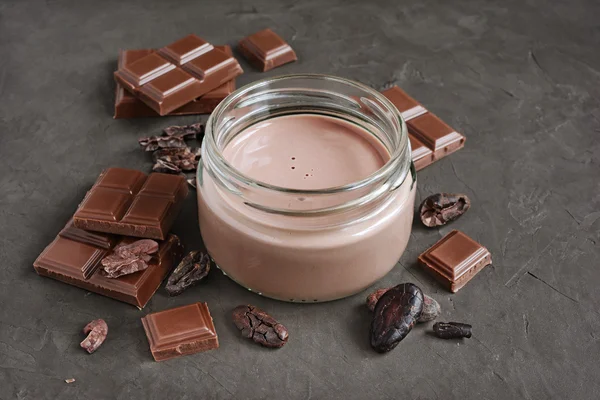 Chocolate milk with pieces of chocolate bar and cacao beans — Stock Photo, Image