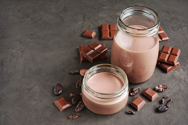 Leche de chocolate con trozos de barra de chocolate y granos de cacao — Foto de Stock