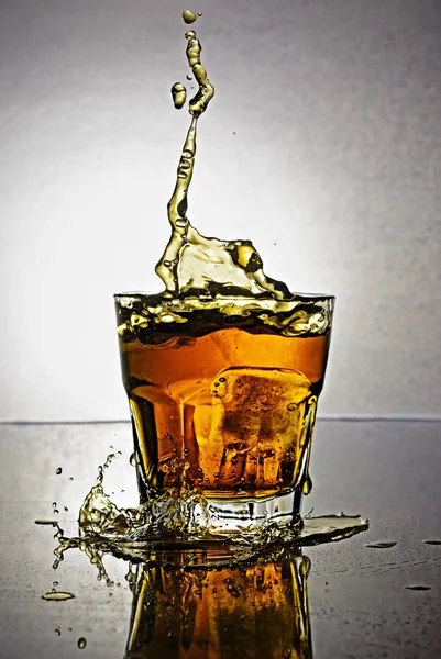 Splash in glass of scotch whiskey with ice — Stock Photo, Image