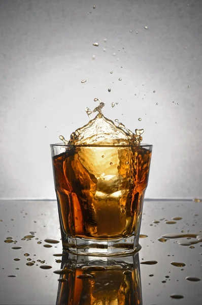 Splash in glass of scotch whiskey with ice — Stock Photo, Image