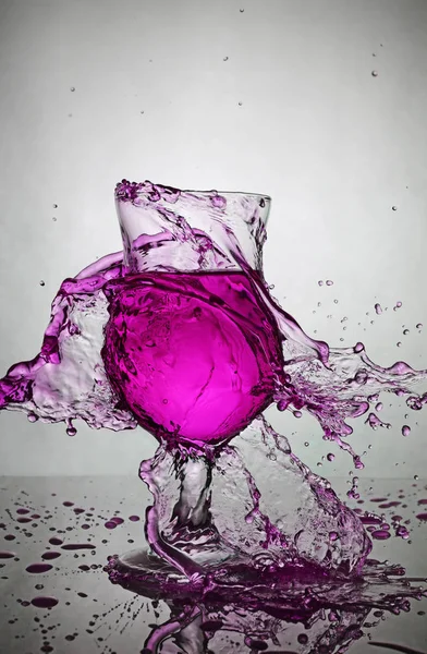 Splash in glass of purple alcoholic cocktail drink