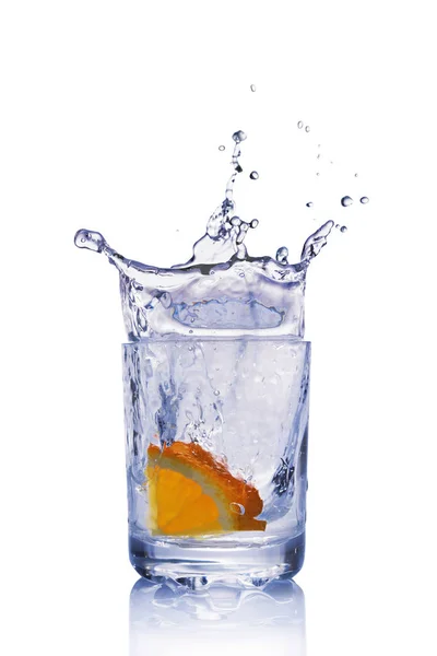 Spritzer in einem Glas blauen Wassers mit Orangenscheibe — Stockfoto