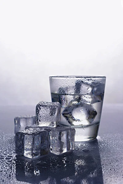 Shot glass of alcoholic drink as tequila or vodka with ice cube — Stock Photo, Image