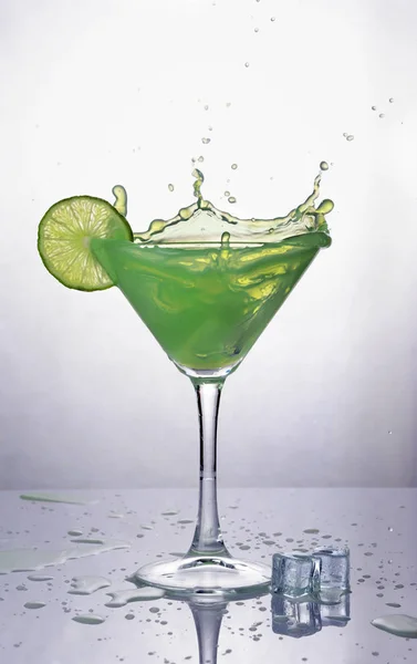 Splash in glass of green mint alcoholic cocktail drink with lime and ice cube — Stock Photo, Image