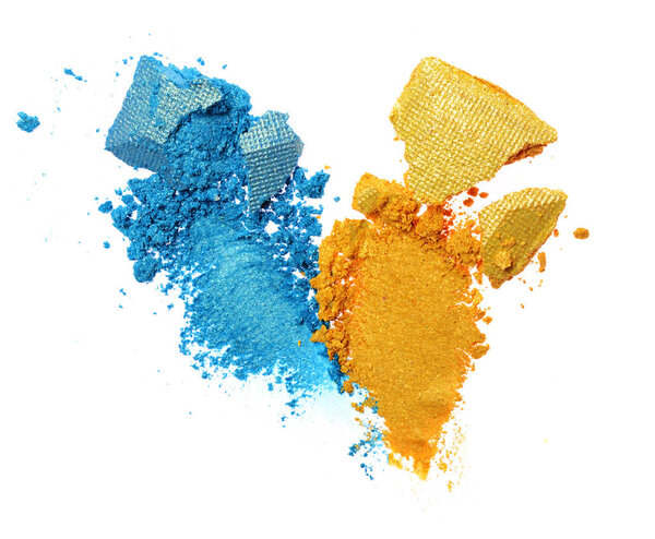 Smears of crushed blue and golden shiny eyeshadow as sample of cosmetic product