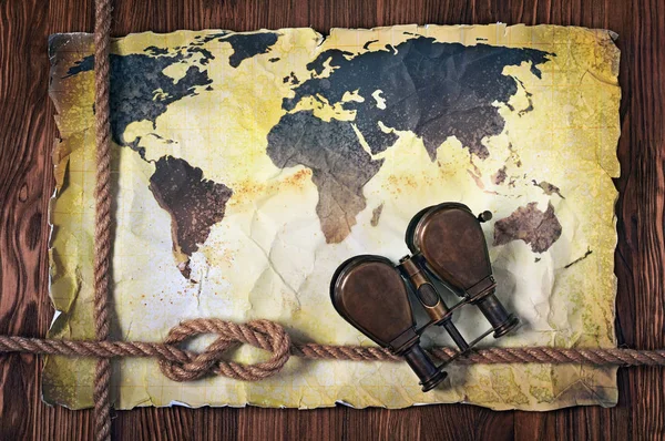 Velho mapa do mundo em papel manchado retro amarelo com binóculos vintage e nó de corda — Fotografia de Stock