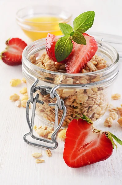 Healthy breakfast. Homemade granola in glass jar with fresh strawberry, mint and honey — Stock Photo, Image