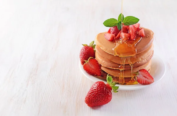 Smakelijk ontbijt. Huisgemaakte pannenkoeken met verse aardbeien, honing en munt — Stockfoto