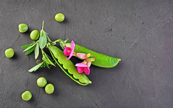 Cibo sano. Piselli verdi freschi con fiori rosa di pisello dolce — Foto Stock