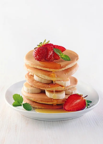 Leckeres Frühstück. hausgemachte Pfannkuchen mit frischen Erdbeeren und Bananen, Honig und Minze — Stockfoto