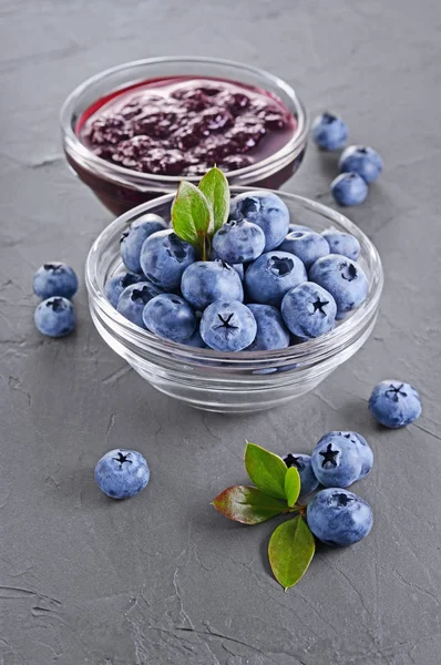 På nära håll se sylt i glasskål med färska mogna blåbär och blad — Stockfoto