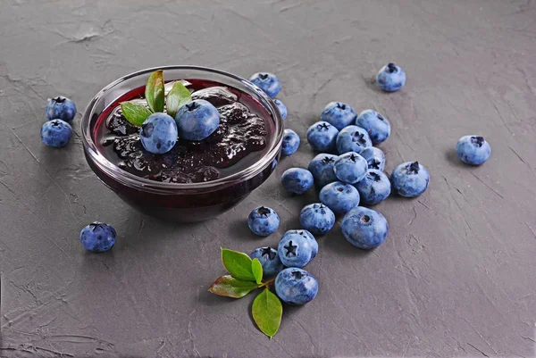 På nära håll se sylt i glasskål med färska mogna blåbär och blad — Stockfoto