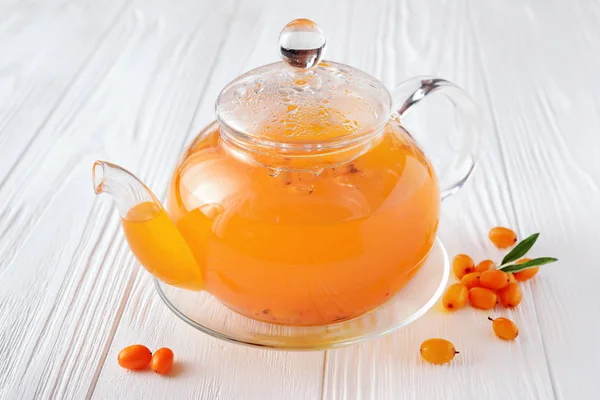 Deniz cehri çay ahşap arka plan üzerinde taze çilek ile cam çaydanlık