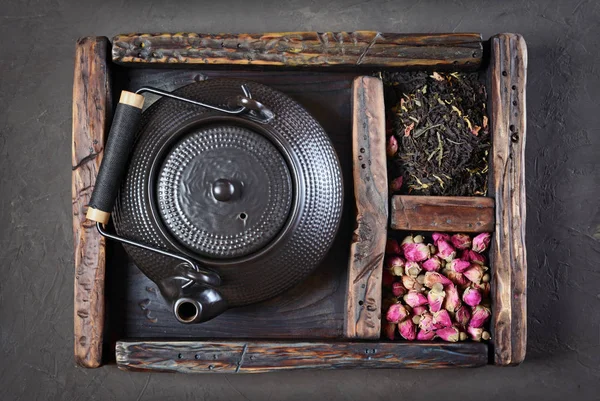 Asian black traditional teapot with dry tea and rose in vintage wooden box — Stock Photo, Image